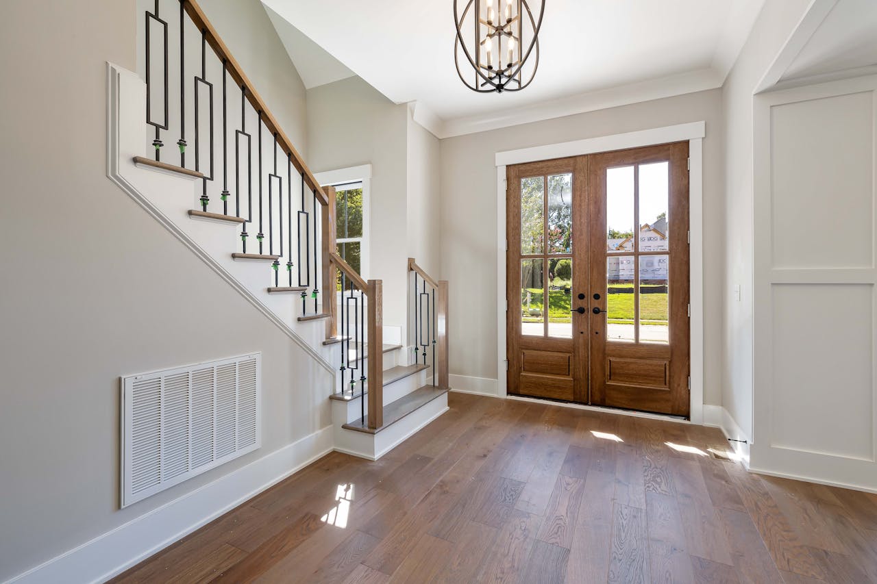 Elegant and spacious house entrance featuring wooden doors and staircase.